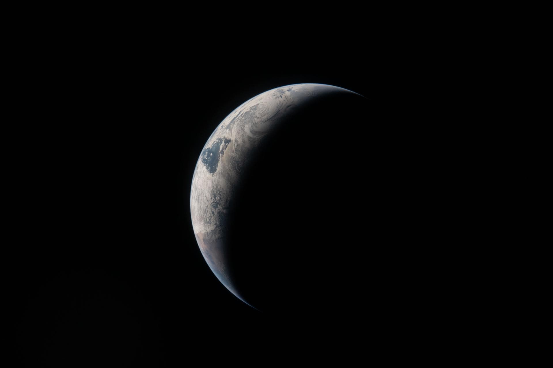 Earth seen as a thin illuminated crescent from the Orion spacecraft near the Moon