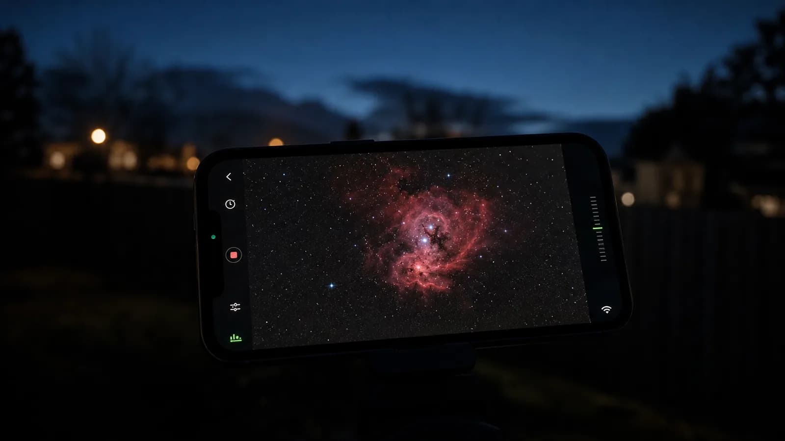 Smartphone in a suburban backyard showing the Seestar app live-stacking a colorful nebula image on screen